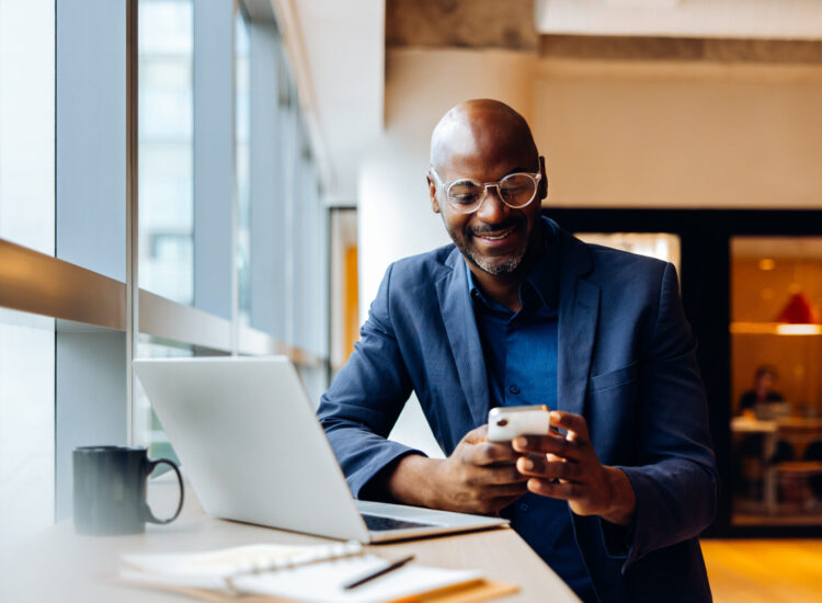 Homme assis smartphone à la main face à son ordinateur