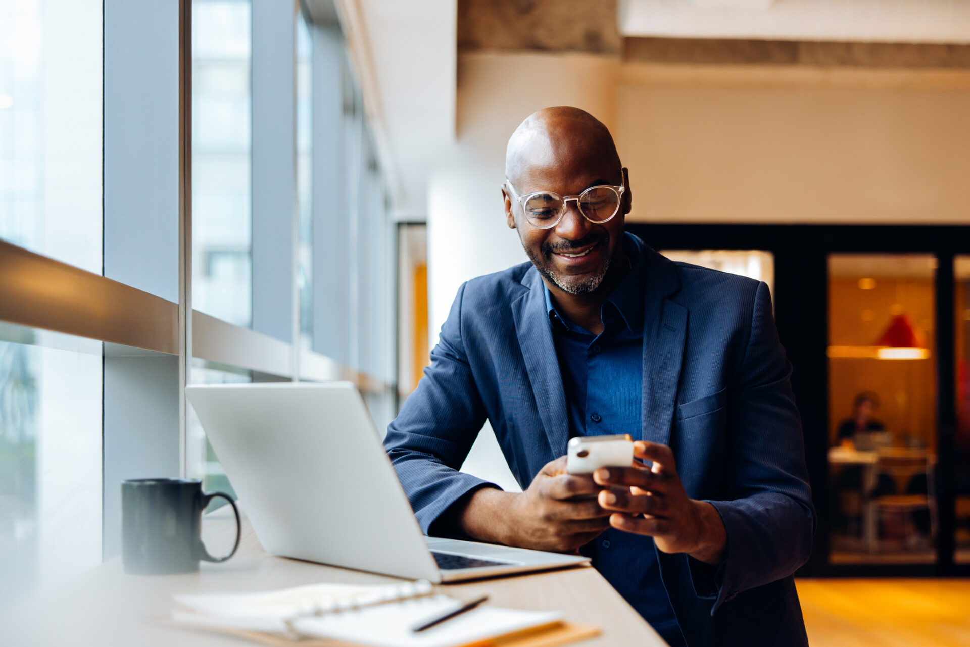 Homme assis smartphone à la main face à son ordinateur
